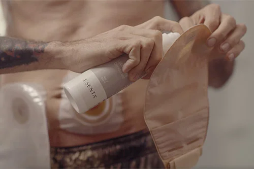 a man spraying a product onto an ostomy pouch