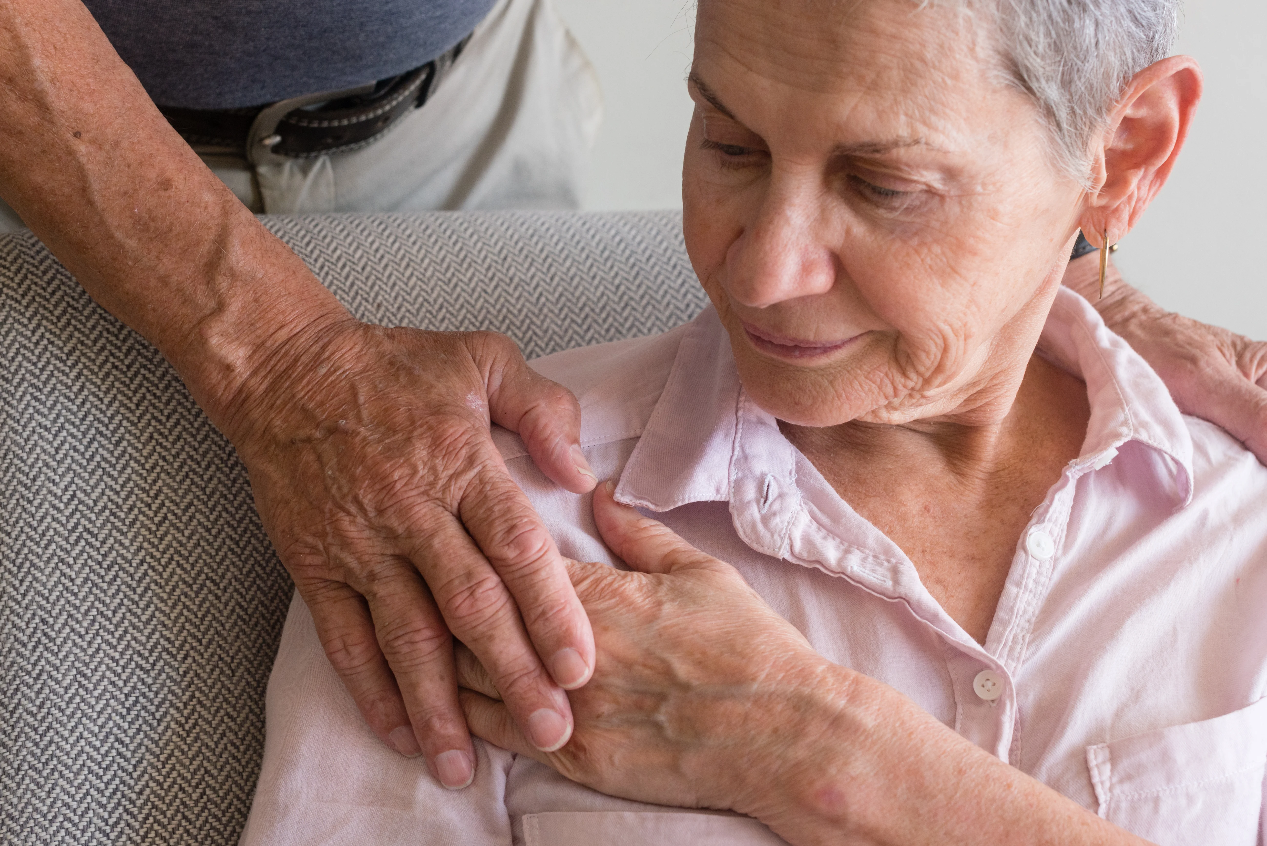 A woman is holding a man's hand on her shoulder