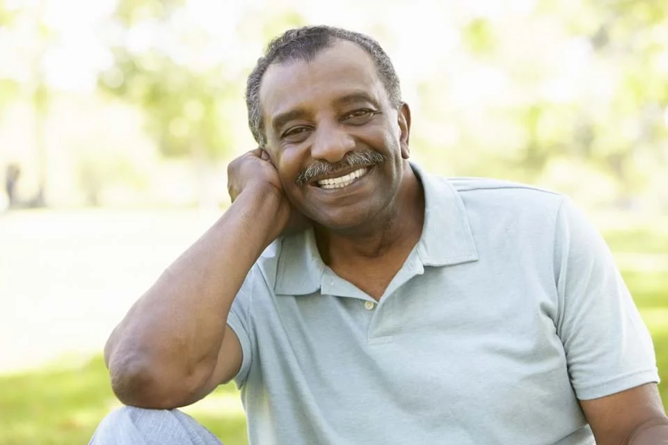 Un hombre sonriendo con la mano en la cabeza